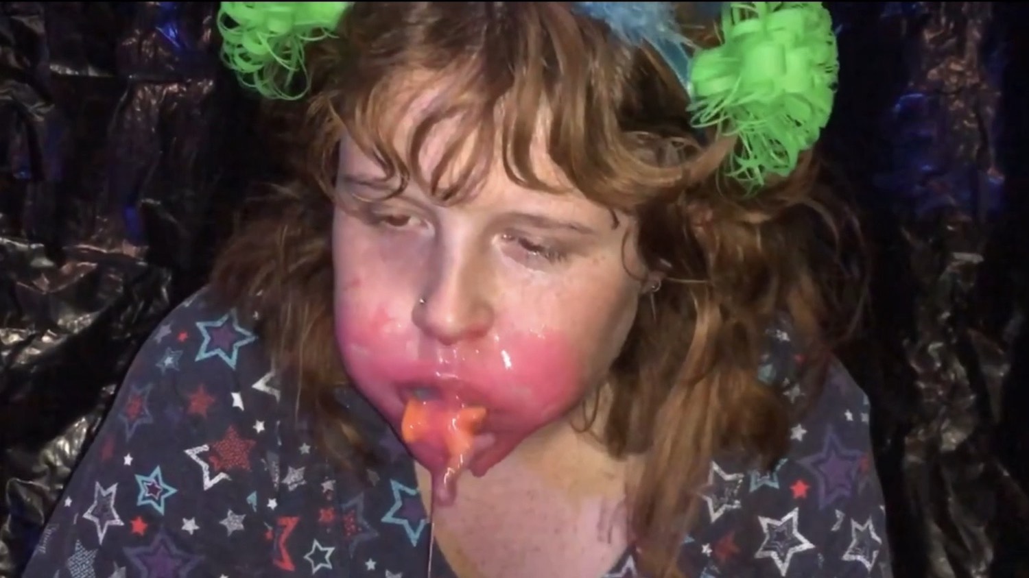 girl with a pink substance smeared across her mouth with her mouth full
