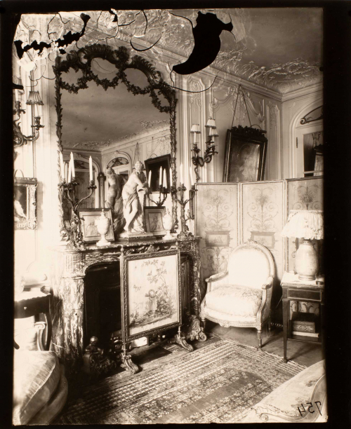 Lavishly decorated interior with marble gilded and filigreed elements mantel and mirror left. Chair, lamp, and screen on right