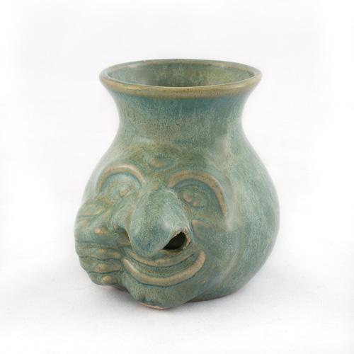 green glazed "face jug". right hand pulls at the mouth and right nostril 