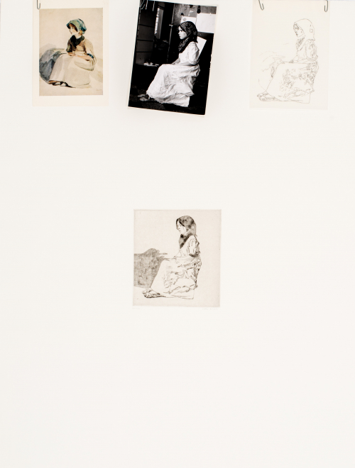 Center small print of a girl sitting, three separate images which resemble the print are paper clipped along the top edge 