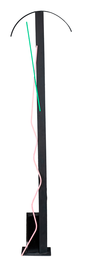A vertical geometrical sculpture, primarily black with green and pink accent colors. Resembles lamp.