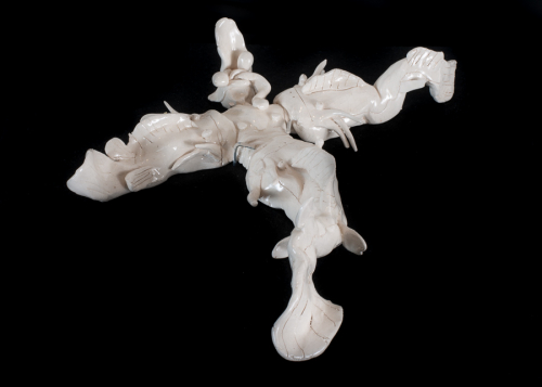 White porcelain work, mounted on black felt-covered wood; piece is of three catfish attacking a creature