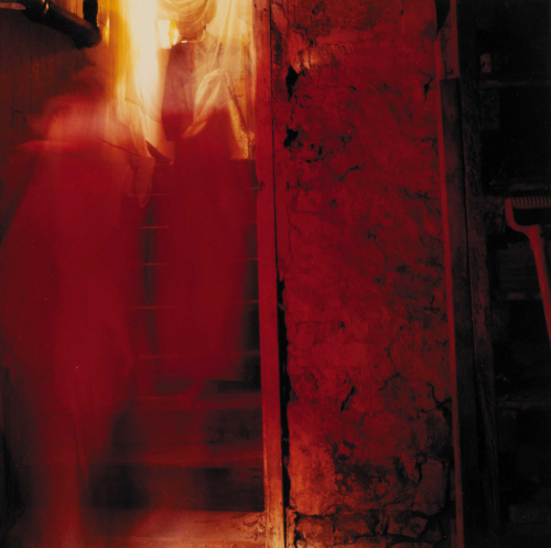 Red and orange photograph blurry resembles figures going up stairs