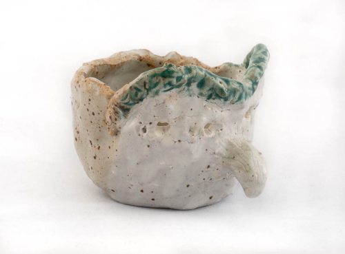 tiny white "face jug" with a hooked nose and a green rim.