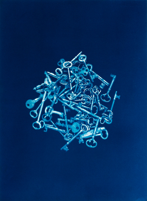 High contrast all blue image of a circular pile of keys centrally located in the composition. 