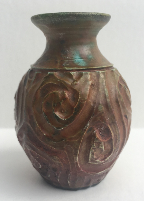A tiny bud vases, primarily orange with deep incisions in swirl patterns.