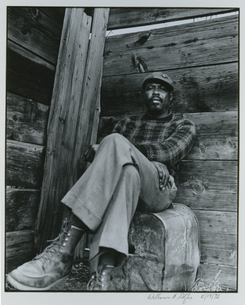 Black man with beard sitting with his legs and arms crossed