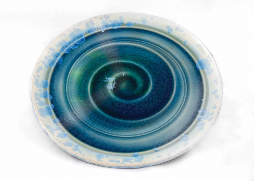 large shallow platter with a swirl pattern of crystalline glaze in greens and blues with a mostly white rim
