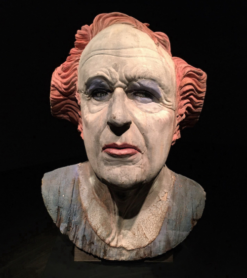 Front: A bust of a white-faced figure with red hair