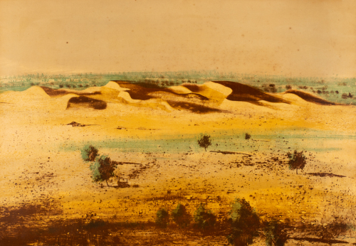 Desolate landscape with a few trees on brown, rocky land with sand dunes in background. mostly yellow and browns a little green