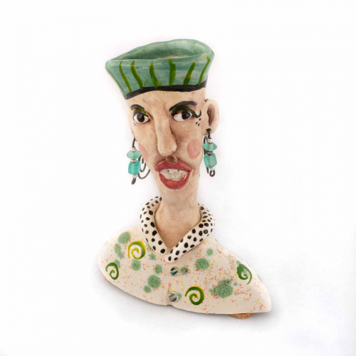 small bust (shoulders up) of a person wearing beaded dangling wire earrings, polka dot top and green hat.