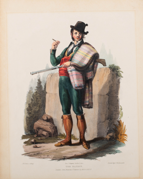 Man standing holding cigar in right hand, rifle in left hand; blanket thrown over left shoulder; rock wall in background