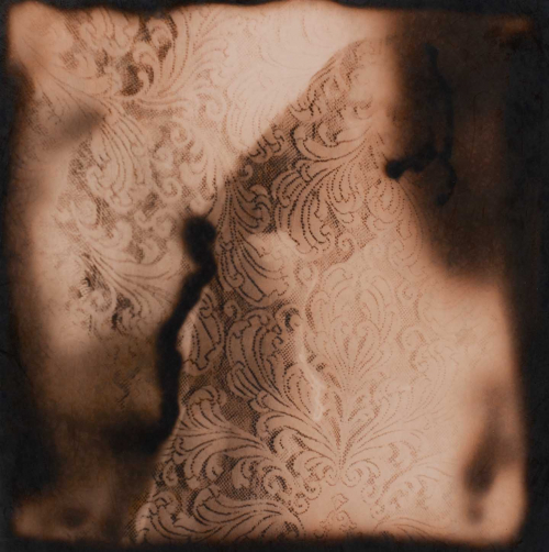 A small sepia image of lace with mottled shadows.