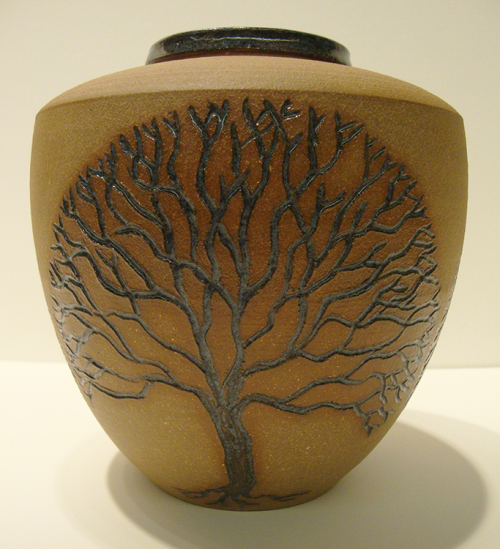 A light brown ovoid pot with the shape of a tree incised into the body in a dark brown