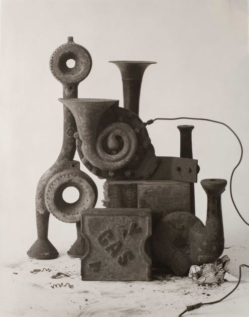 Combination of various objects in a still life on white background; one object reads, "gas", some dirt on ground