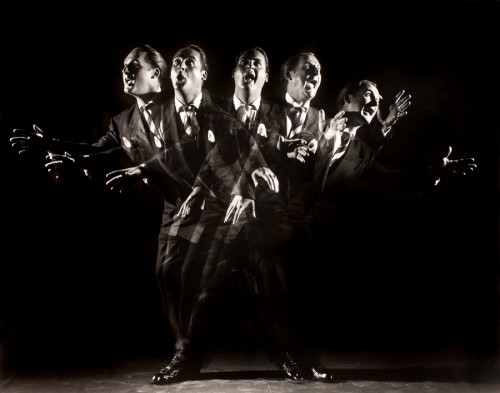 multiple exposure of man in suite in front of dark background standing in center, in various poses 
