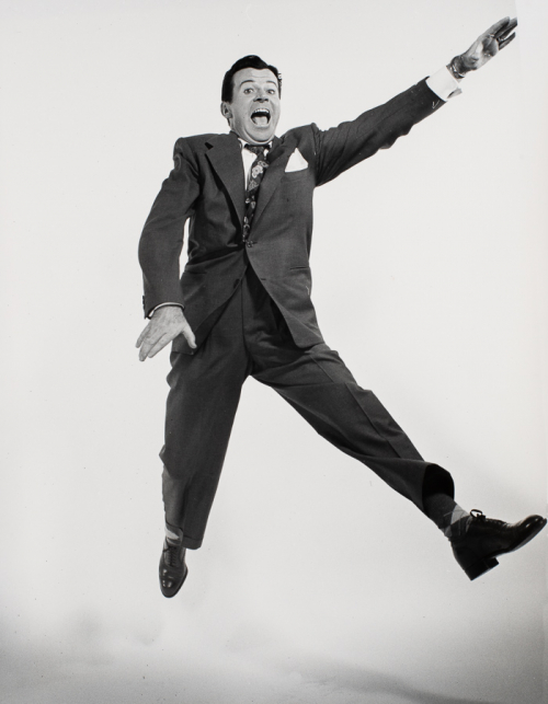 man jumping in mid-air with left arm outstretched straight upward and left leg extended straight downward, right leg bent back