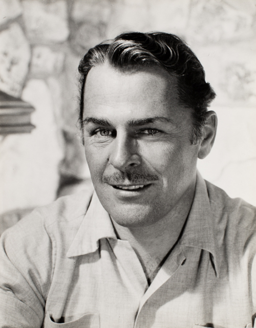 Bust of man in lined shirt facing viewer with head turned slightly to the left side of the image and smiling slightly.