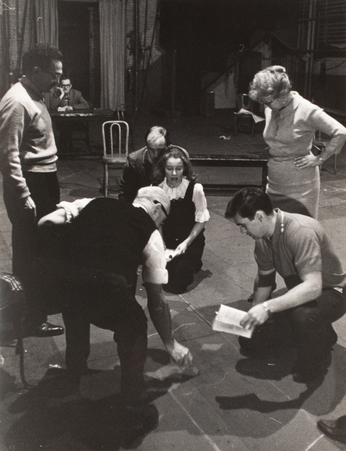 Group of six people on what is probably a stage.  Five people in various positions encircle a female kneeling facing the viewer 