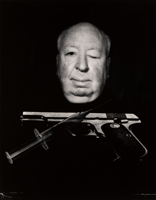 Winking face of Alfred Hitchcock emerging from black background, gun and syringe crossed below