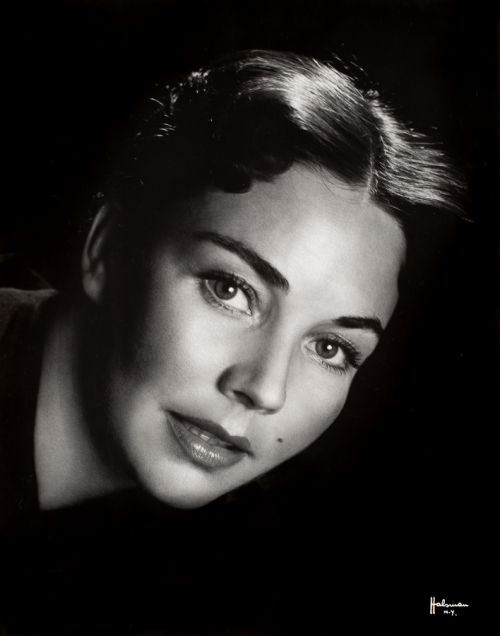 Head of woman leaning into picture plane from left side Face and eyes are directed towards the viewer.  Dark background