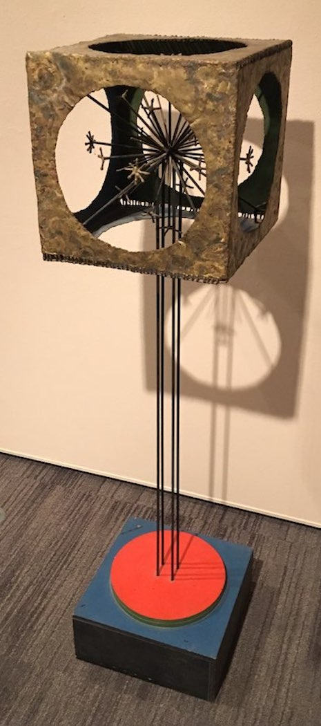 A large metal sculpture with a polychromed wooden base