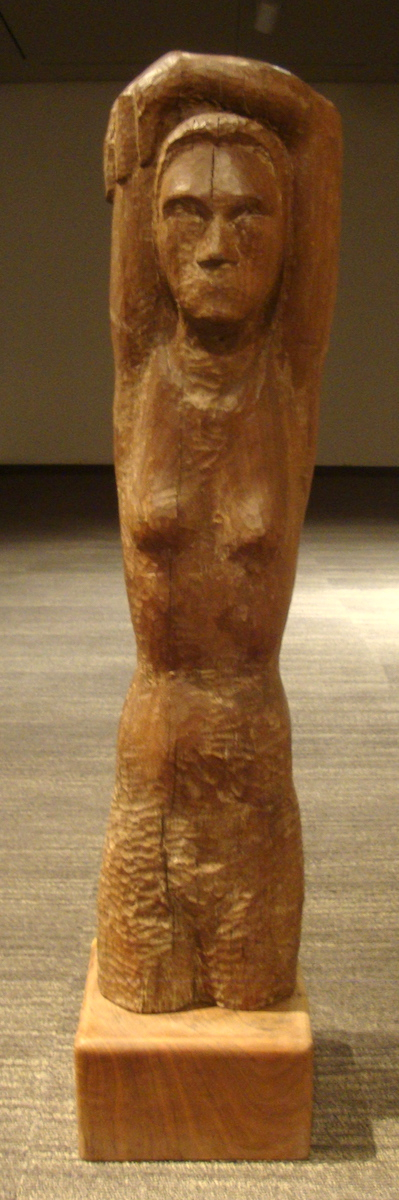 A narrow, cylindrical carving that depicts an abstracted nude female form