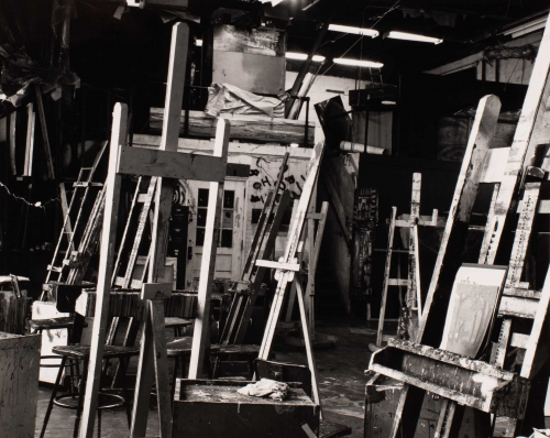 Black and white image of interior of painting studio with several empty easels