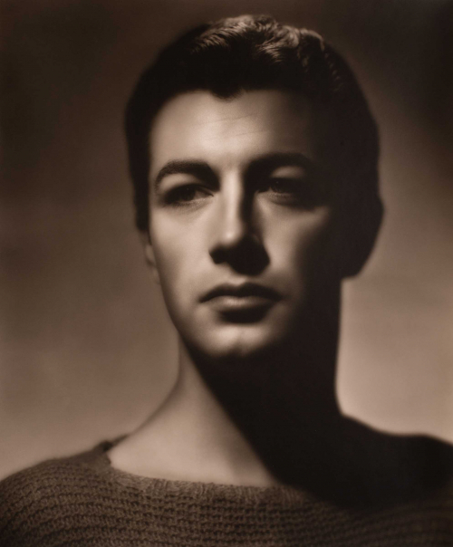 Head and shoulders of man in sweater with eyes cast towards left of image