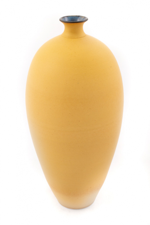 A tall, narrow, egg-shaped vase decorated in a matte, light yellow with a shiny blue mouth.
