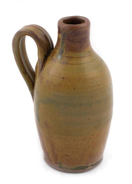 small jug with a large handle glazed in a caramel beige, darker at the neck and rim.