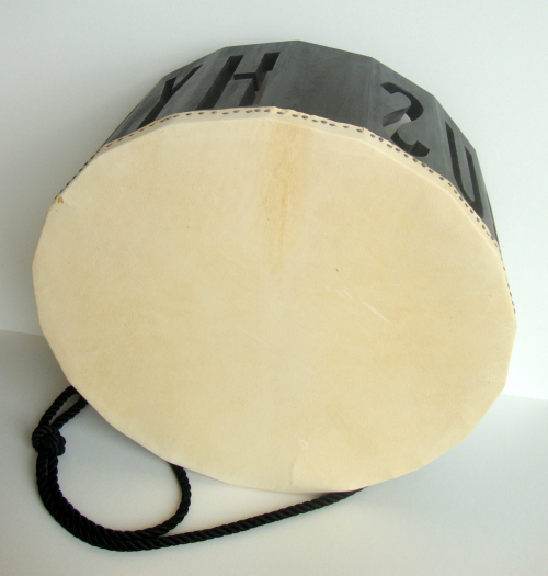 A drum-shaped sculpture with black sides that have carved out letters