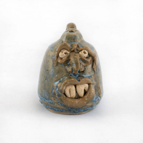 tiny blue face jug with a handle, small opening, and prominent teeth.