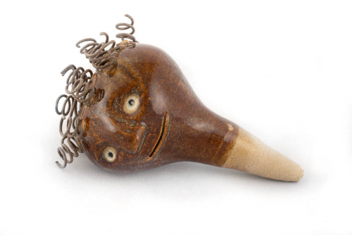 small sculpture in the shape of a bottle stopper inspired by the "face jug" form with prominent curled wire hair.