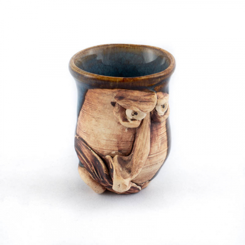 tiny face jug in form of a cup with a blue interior and brown exterior. Face has a prominent nose and mustache skewed to left