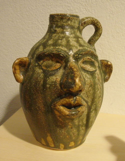 A green face jug with vertical streaks of glazing