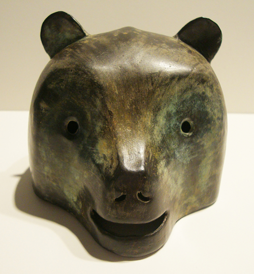 A small sculpture of a bear head in a dark brown and green patina