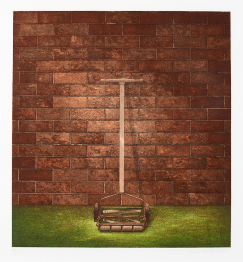 Old-fashioned grass cutter leaning against a brick wall