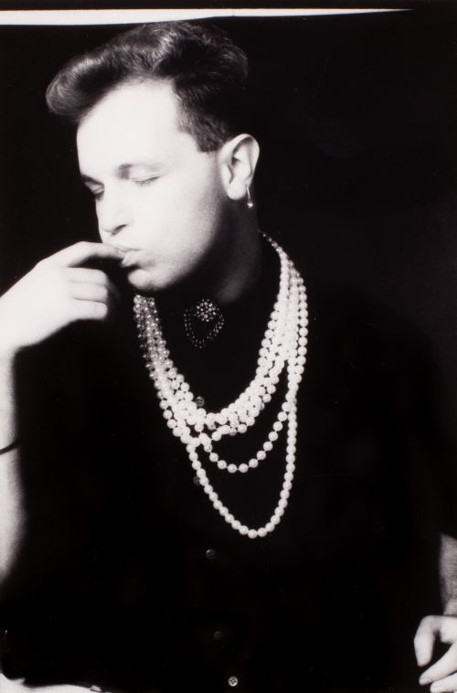 A male figure in 3/4 profile wearing strings of pearls