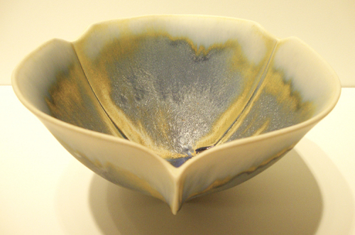 A sculptural bowl on tripod feet, glazed in blue and yellow with a white rim