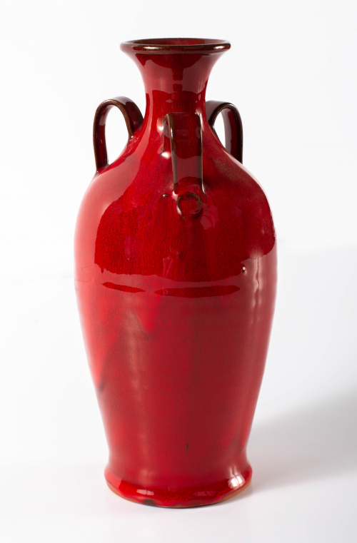 A slender vase with a shiny bright red glaze and three small handles at the shoulders.