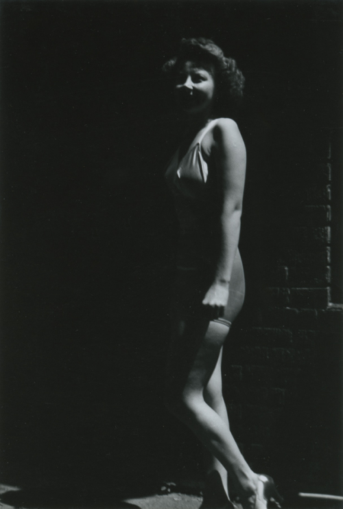 Very shadowed full-length black and white photograph of a woman