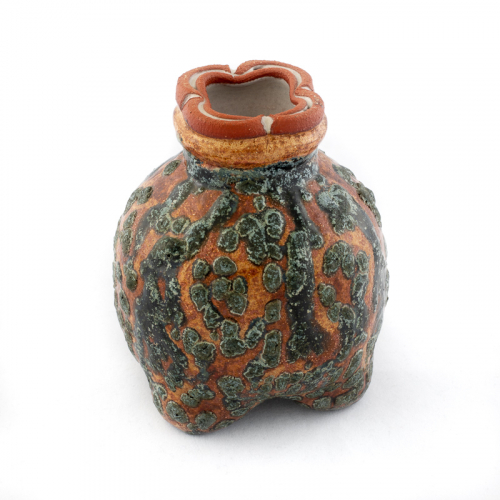 small vase highly textured with orange, gray, and white glazes. the base is a tripod and the mouth in clover shape