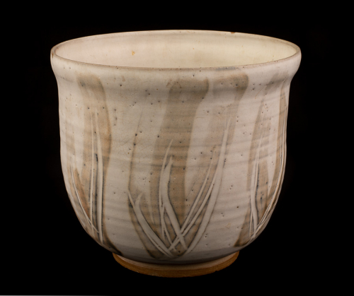  large white cylindrical bowl with light tan vertical, but curvilinear, markings on the outer body. The base has no glazing.