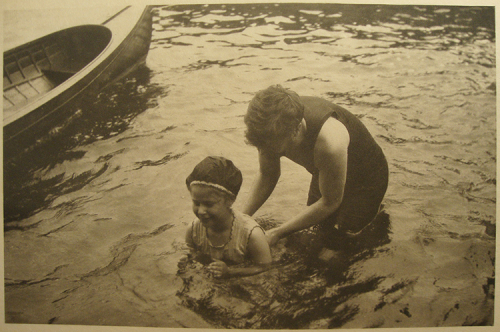 Two female figures in shallow water beside a boat.