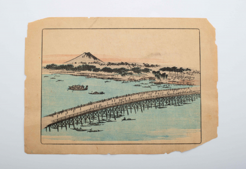 Aerial view of a long bridge spanning a body of water with Mt. Fuji in the distance.