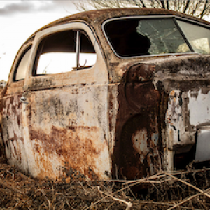 rusted car body in a field